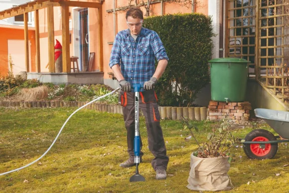 Person verwendet einen Bodenausstecher im Garten.